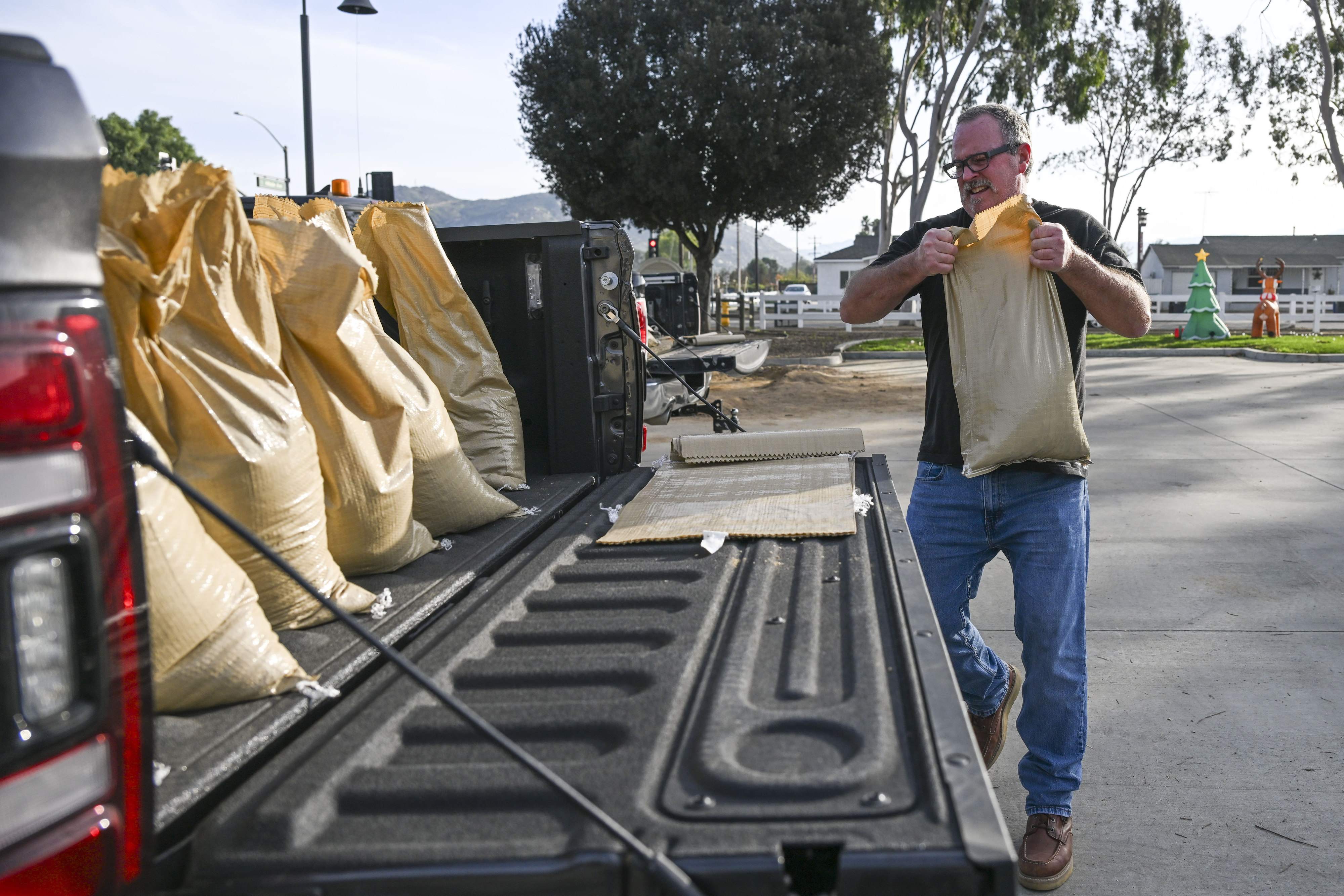 Norco resident Terry McCauley fills his truck with sandbags at...