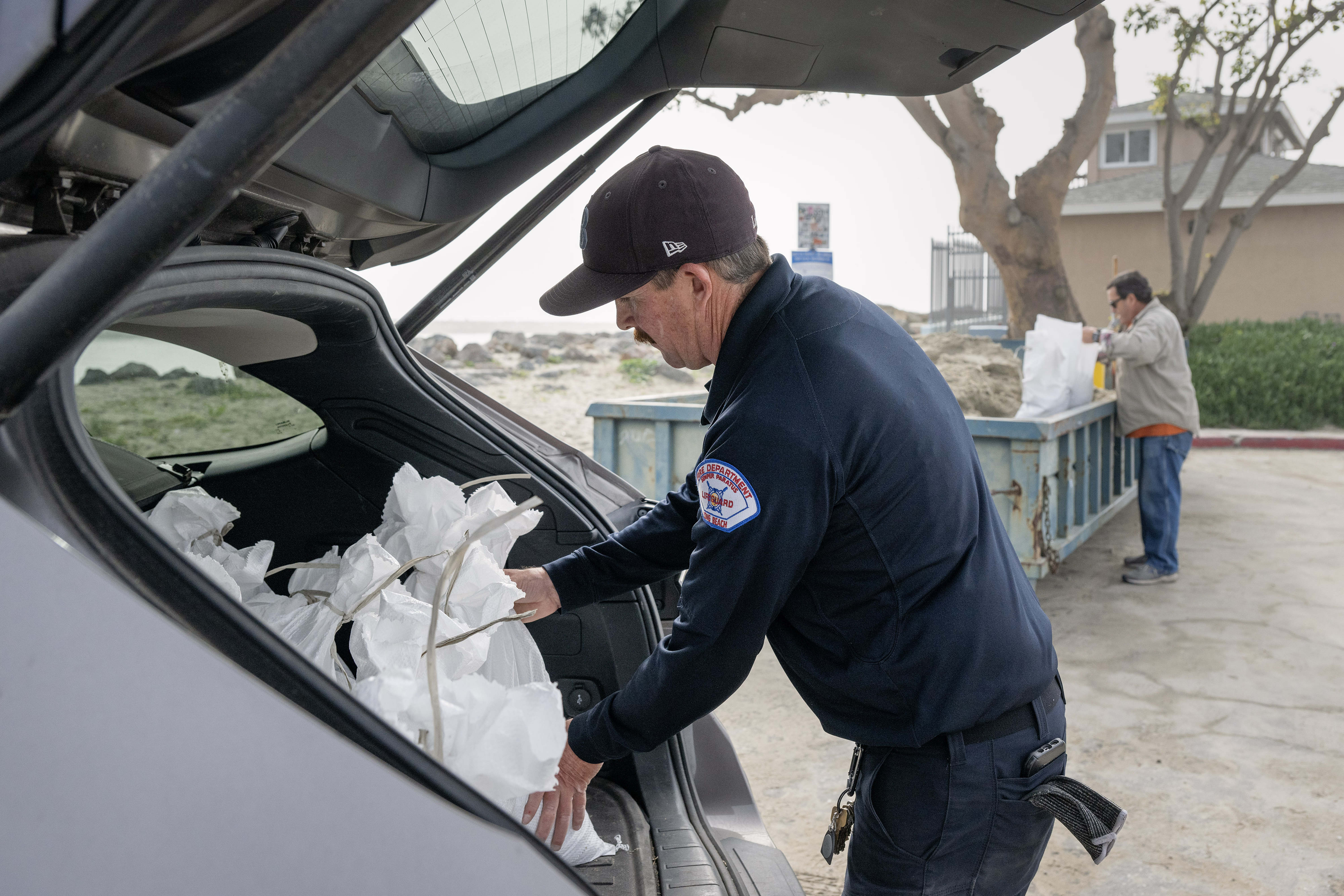Ocean Lifeguard Sean Guerin loads sandbags outside the 72nd Place...