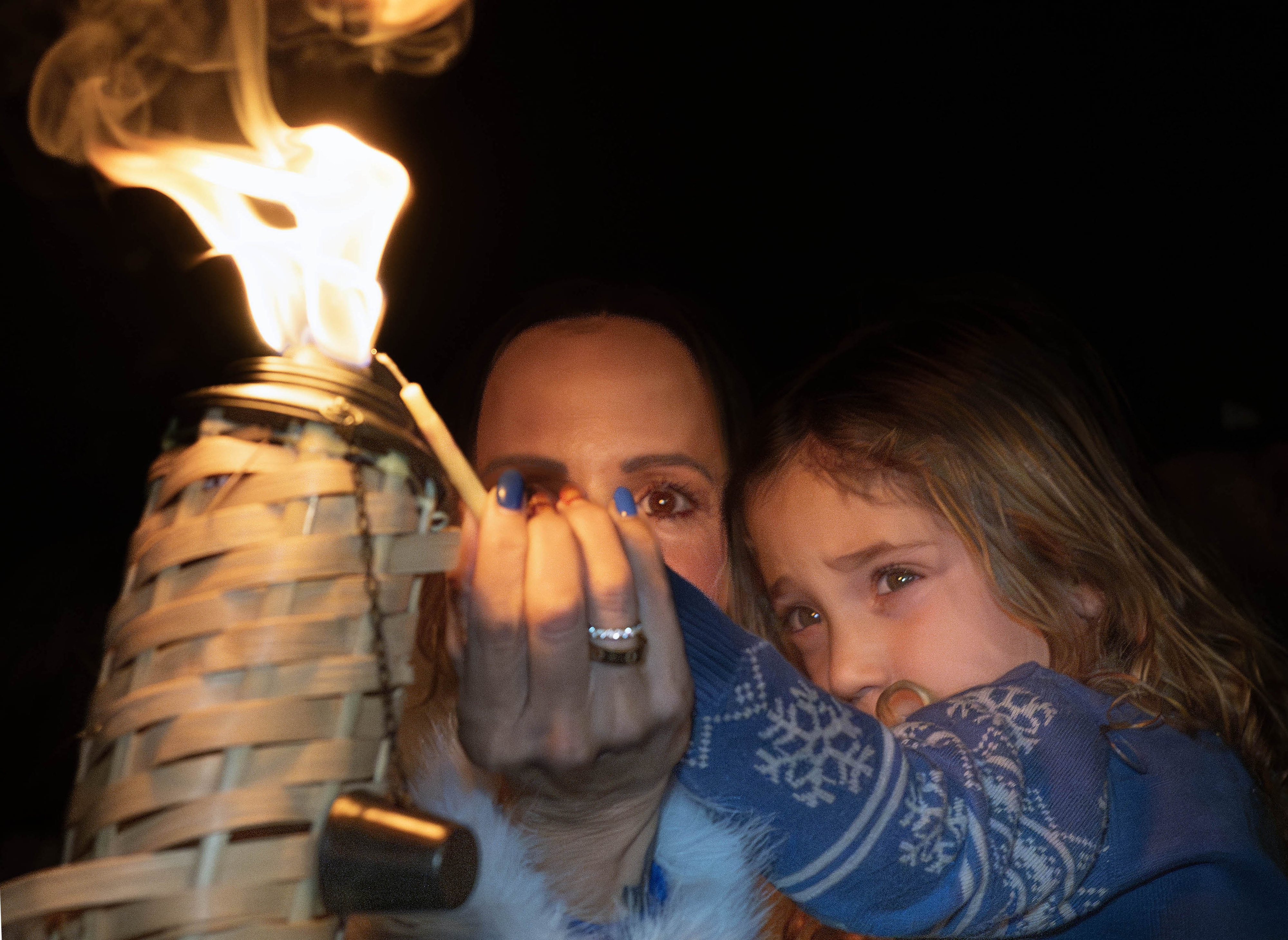 Liz Shindel and her 3-year-old niece, Charlie, light a candle...