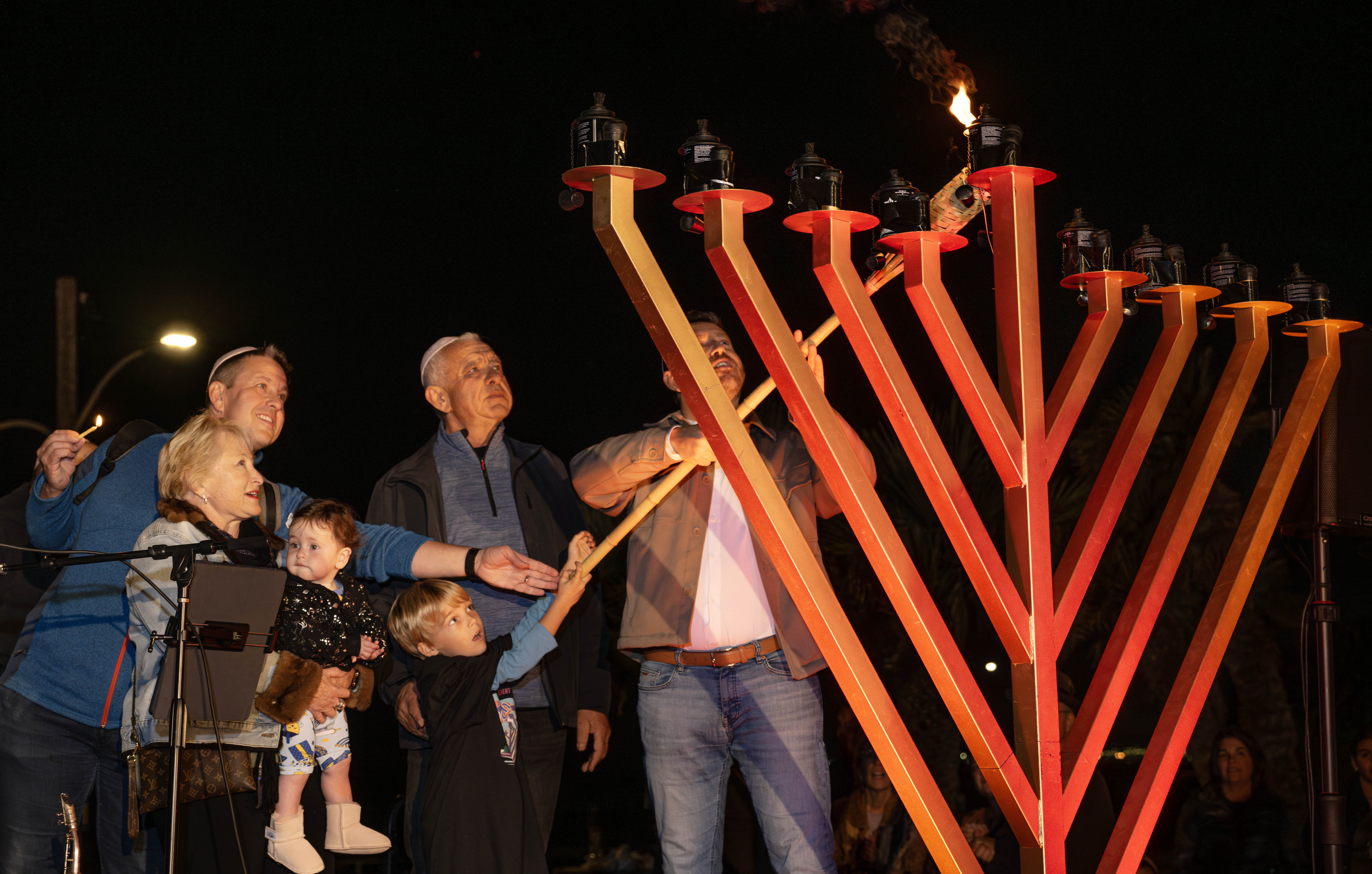 The Reyngold family lights the shamash during the annual pre-Hanukkah...