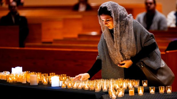 A volunteer places a candle on a table to represent one of the 511 homeless persons that died in in Orange County in 2023 during the Homeless Persons' Inter-Religious Memorial Service at St. Timothy's Catholic Church in Laguna Niguel on Thursday, Dec. 21, 2023. (Photo by Leonard Ortiz, Orange County Register/SCNG)