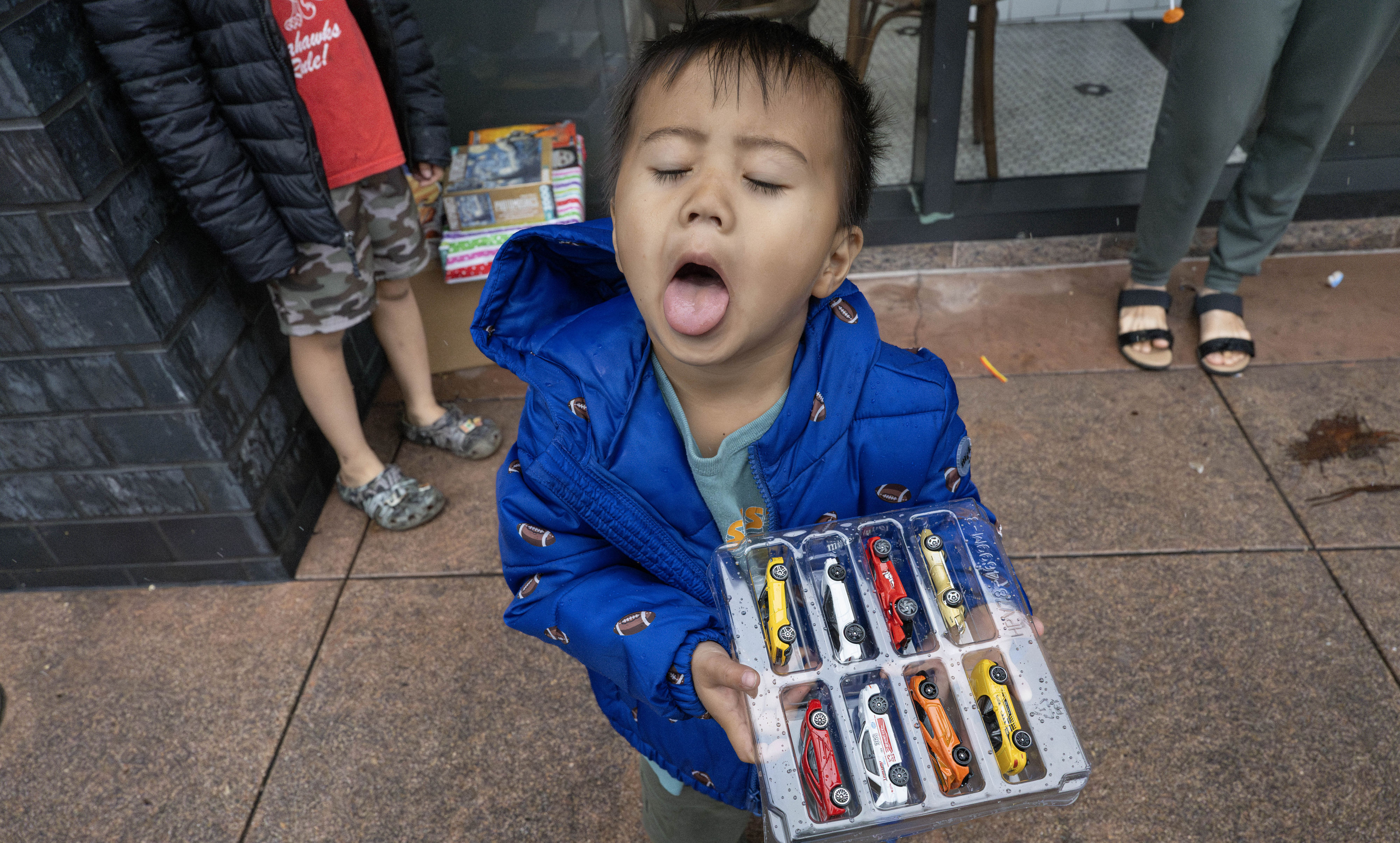 Three-year-old Dalton Pham catches raindrops after receiving gifts, including a...