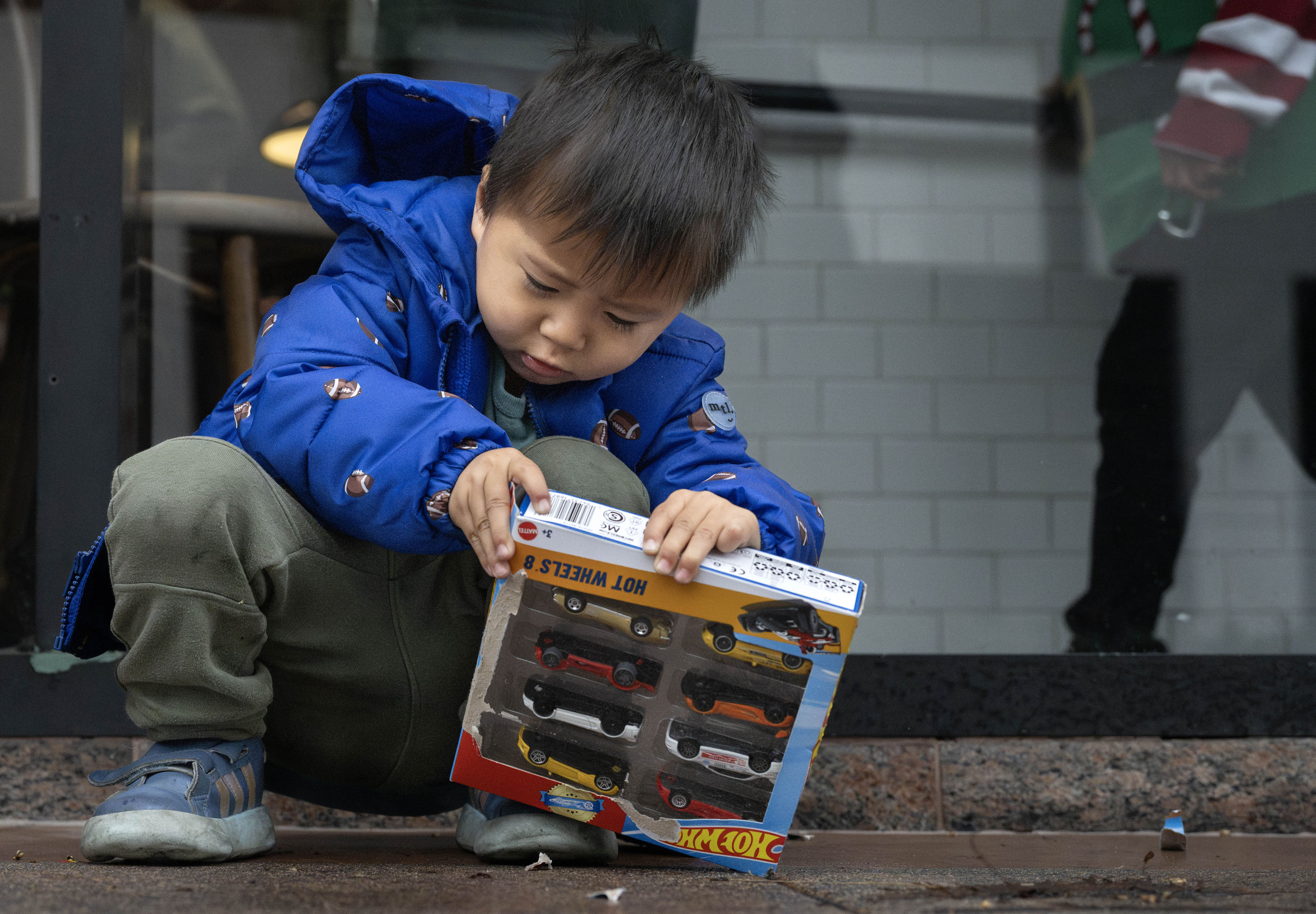 Three-year-old Dalton Pham concentrates on opening his Hot Wheels gift...
