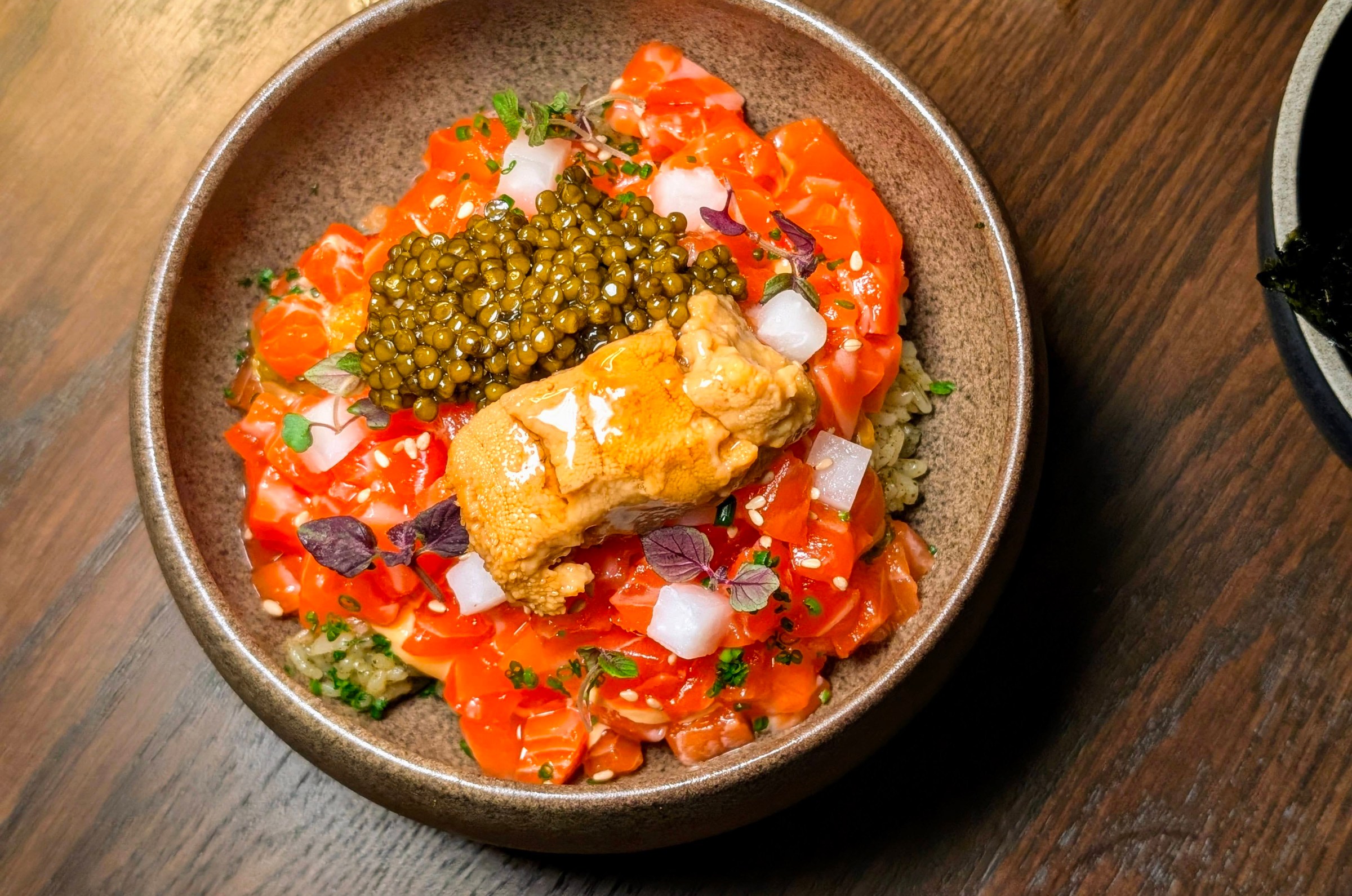 A dish of seasoned rice, raw fish, caviar, and uni at Hojokban in a ceramic bowl.