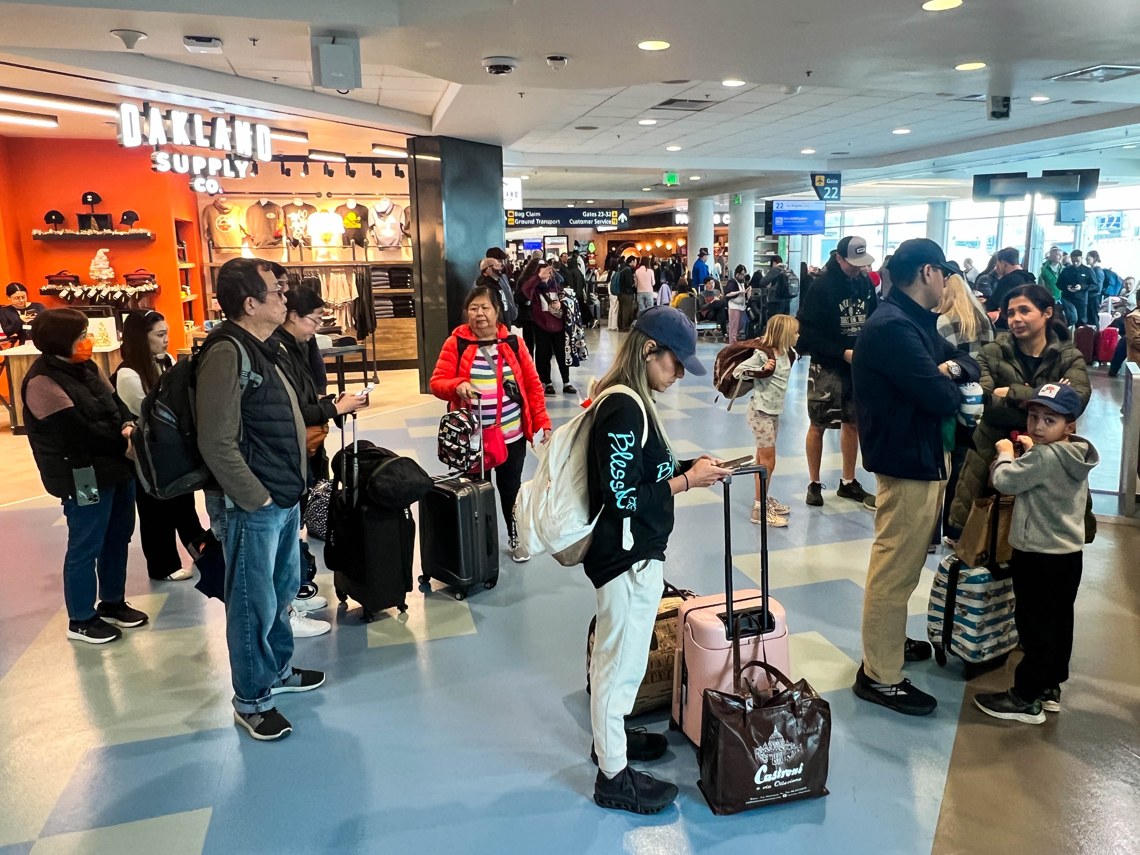 Travelers wait in line to board their flight at the...