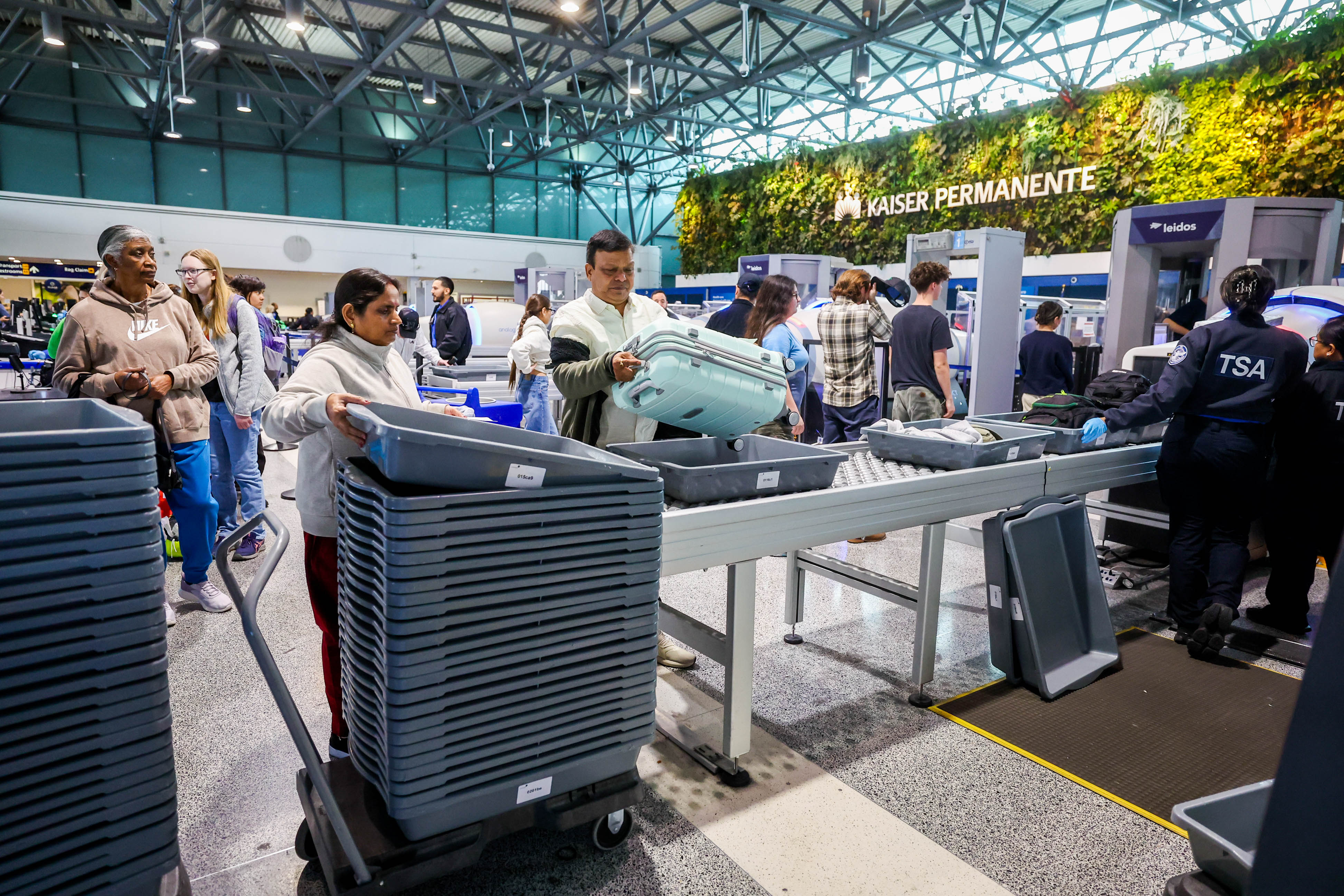 Travelers go through a security checkpoint at the Oakland San...