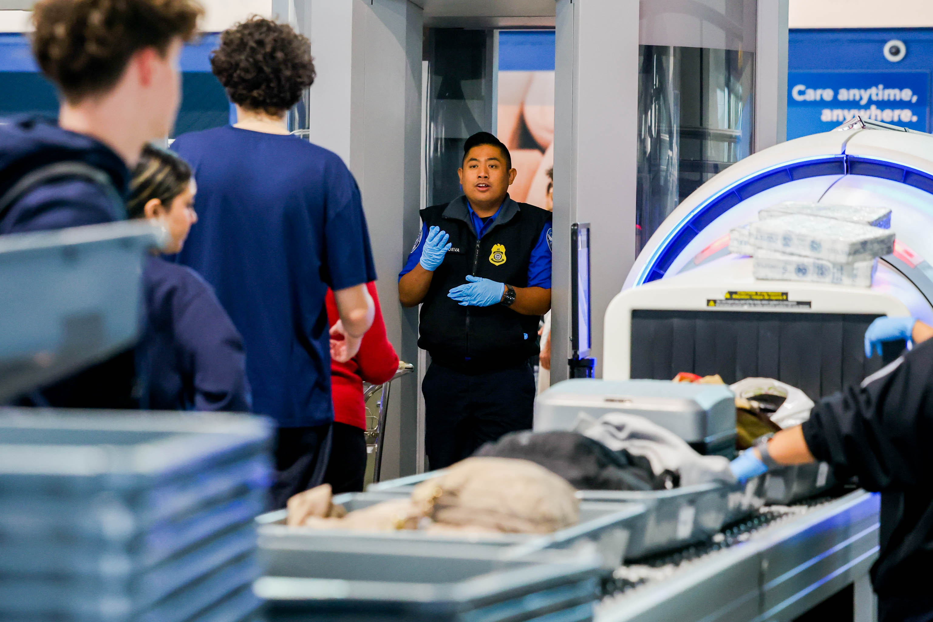 A TSA agent gestures to travelers at a checkpoint screening...