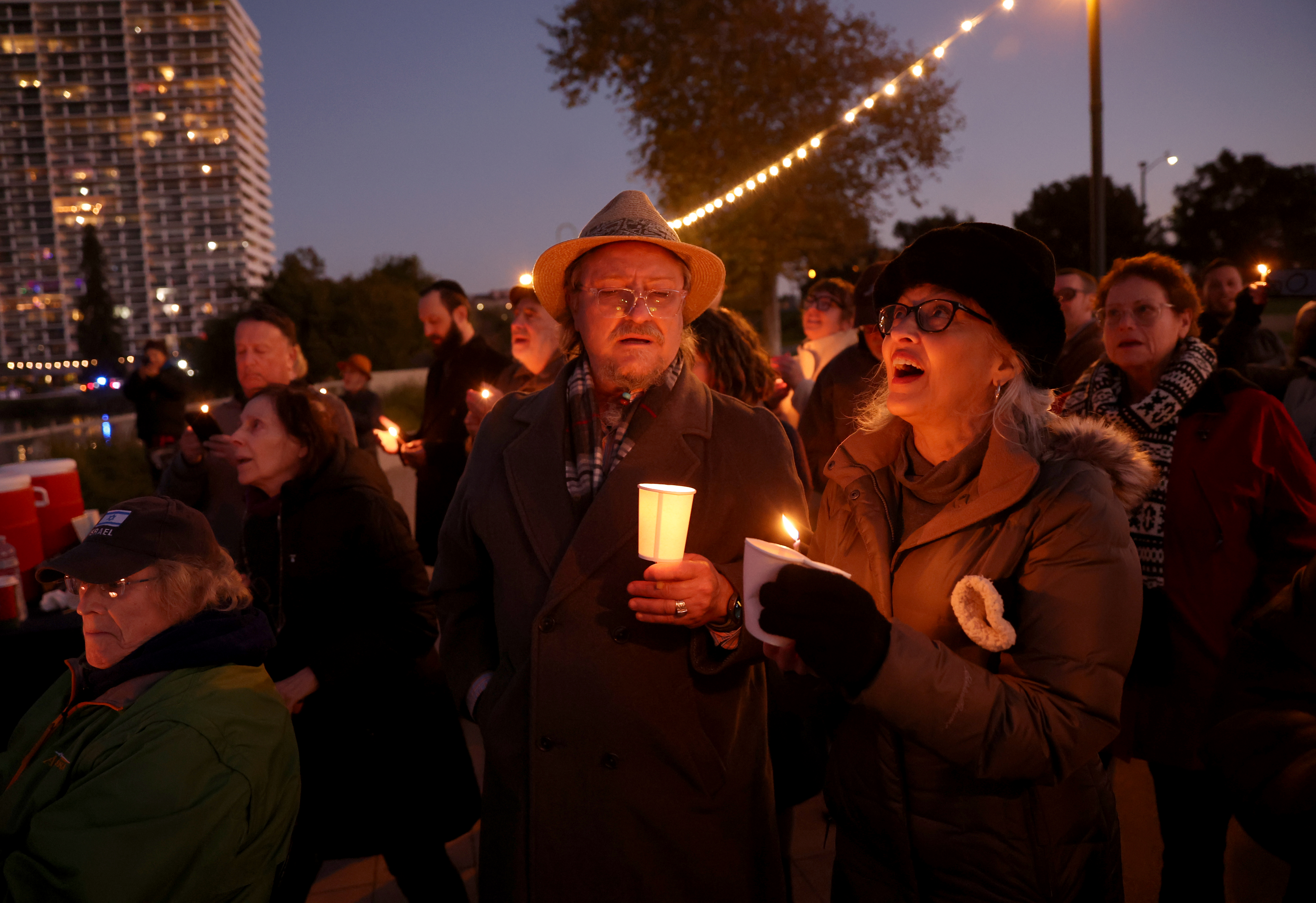 Community members sing during a Hanukkah menorah-lighting ceremony at the...