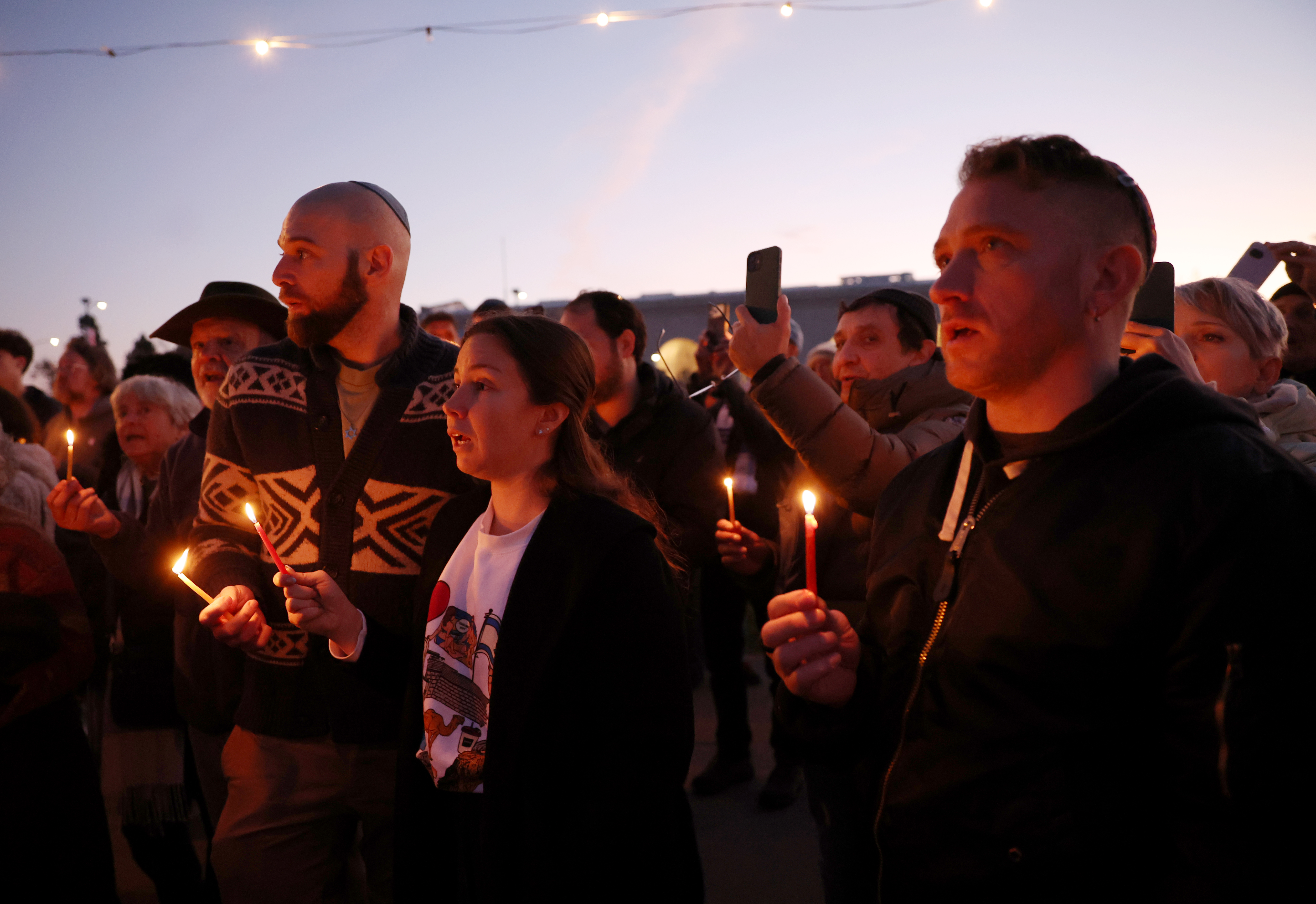 Community members take part in a Hanukkah menorah-lighting ceremony at...