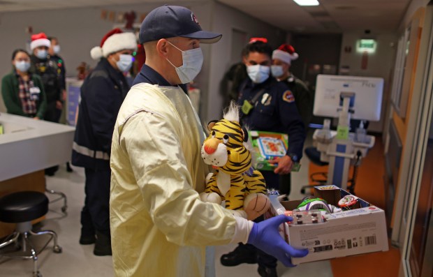 A member of the Santa Clara County Fire Department delivers Christmas gifts in the isolation ward of the Pediatric Intensive Care Unit at Santa Clara Valley Medical Center on Wednesday, Dec. 17, 2025, in San Jose, Calif. (Aric Crabb/Bay Area News Group)