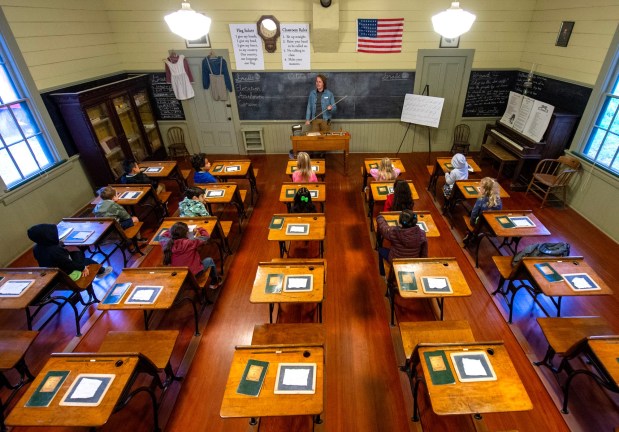Zanker Elementary School students listen to a museum educator inside the Santa Ana School, a former one-room schoolhouse originally located in Hollister, which is now located at History San Jose, to educate children on how classes were held in the 1890s, during a school tour of the park in San Jose, Calif., on Wednesday, Oct. 15, 2025. (Doug Duran/Bay Area News Group)