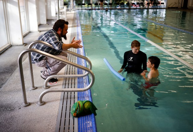 Jason Foreman, from San Jose, asks his son Lucas, 9, if he is done swimming at the end of his lesson taught by Natalie Hand, swim instructor, in the Safety Around Water (SAW) program at the Southwest YMCA in Saratoga, Calif., on Monday, Oct. 26, 2025. Wish Book for the YMCA Safety Around Water program. (Nhat V. Meyer/Bay Area News Group)