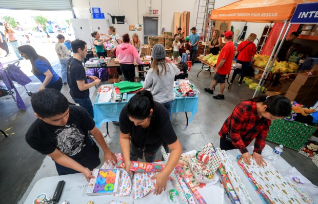 ESCONDIDO, CA - December 13, 2025: Volunteers Monica Guevara and son Julian, 15, both at left, wrap gifts during Interfaith Community Services' annual Winterfaith, a two day event where 250 families in need received food, clothing and Christmas gifts, with the help of around 150 volunteers, at Interfaith Community Services in Escondido on Saturday, December 13, 2025. (Hayne Palmour IV / For The San Diego Union-Tribune)