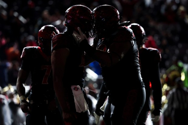 Jayden Denegal #4 and Ross Ulugalu-Maseuli #63 of the San Diego State Aztecs celebrate after a touchdown against the Boise State Broncos during their game at Snapdragon Stadium on Saturday, Nov. 15, 2025 in San Diego, California. (Meg McLaughlin / The San Diego Union-Tribune)