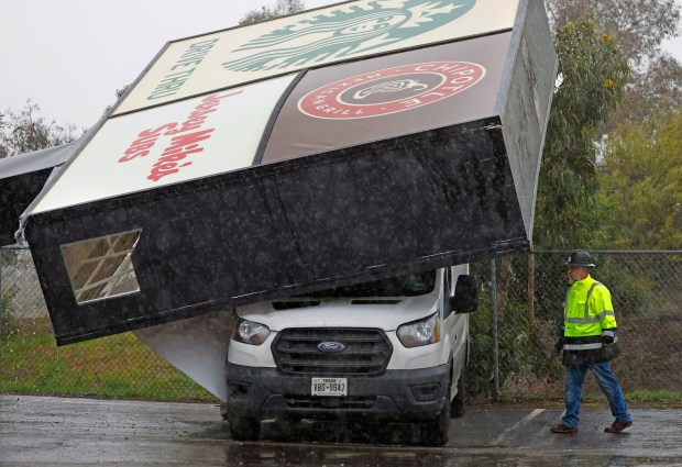 National City, CA - December 24: An advertising sign for Starbucks, Jersey Mike's Subs and Chipotle fell on a sedan and a van (shown) during a wind storm on December 24, 2025 in National City, CA. (K.C. Alfred / The San Diego Union-Tribune)