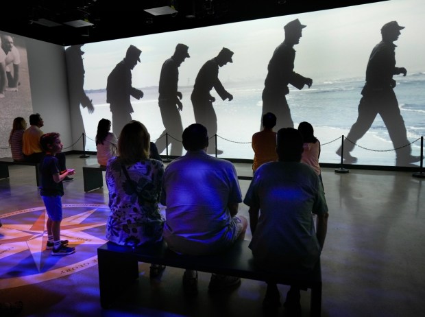 On Saturday, Oct. 4, 2025, in San Diego, visitors attending the grand opening of the Navy SEAL Museum watched a large three-screen display showcasing Navy SEALs in training and in action, including video interviews with former Navy SEALs. (Nelvin C. Cepeda / The San Diego Union-Tribune)