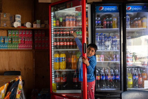 Obed Benjamin Ramos, 8, grabs a soda from his mother's store on Tuesday, April 15, 2025, in Tijuana, Baja California. The El Salvadorian family had planned to seek asylum in the United States but the day of their CBP One appointment a winter storm washed out the road making it impassable. They now have started a new life in Tijuana. (Ana Ramirez / The San Diego Union-Tribune)
