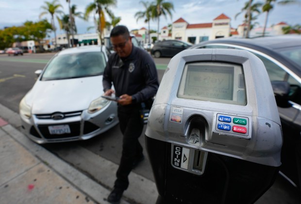 A San Diego parking enforcement officer issues a ticket for an expired meter on University Avenue in Hillcrest on Thursday, Nov. 20, 2025. (Nelvin C. Cepeda / The San Diego Union-Tribune)