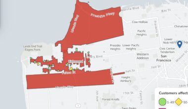 Map showing parts of San Francisco's Presidio and Richmond neighborhoods highlighted in red, indicating areas affected by a power outage. Green and yellow dots show customer impact.