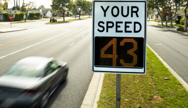 A vehicle zooms past a radar speed display sign.