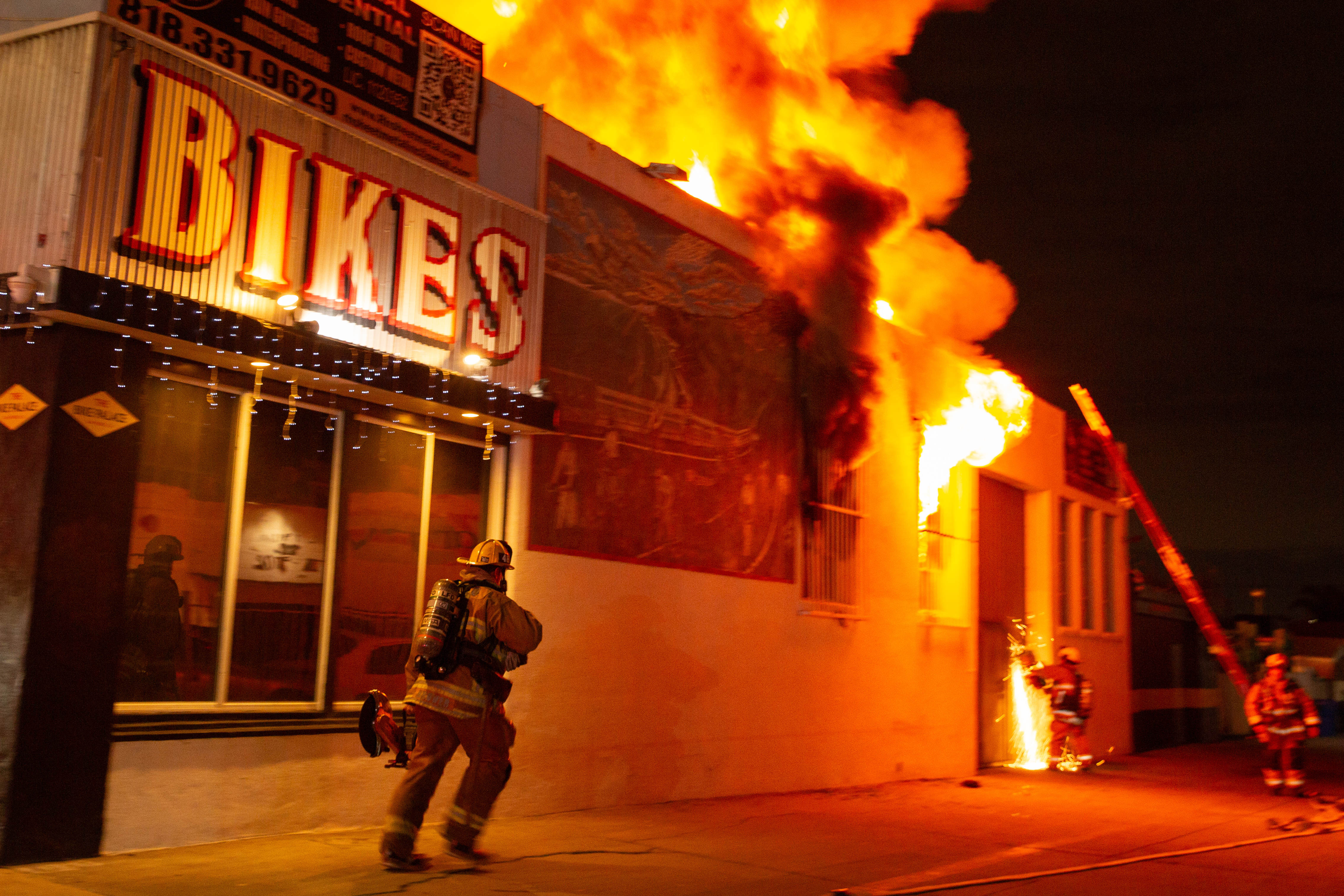 A firefighter runs with a rotary saw as a fire...
