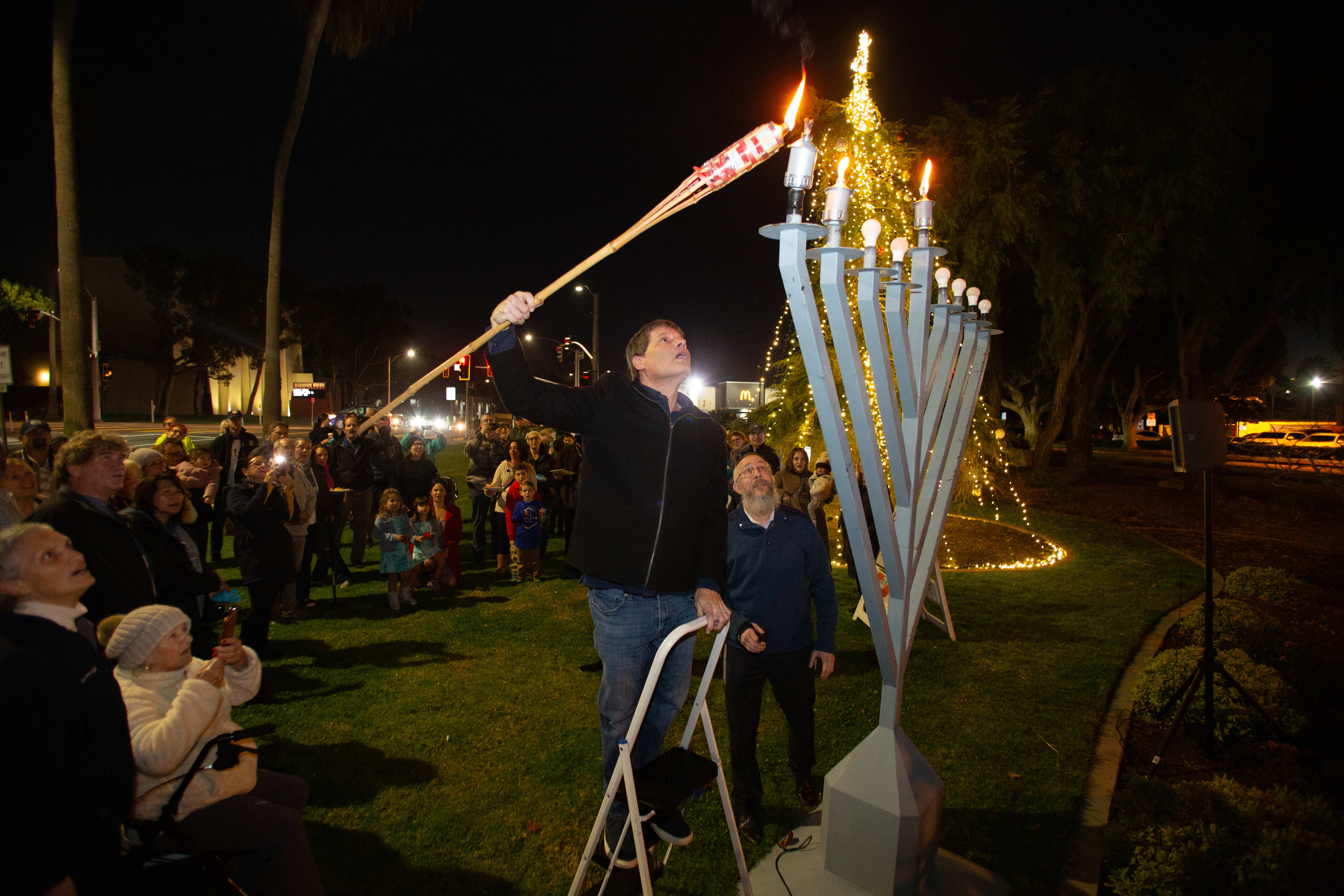 Surrounded by onlookers, Redondo Beach Councilmember Todd Loewenstein lights a...