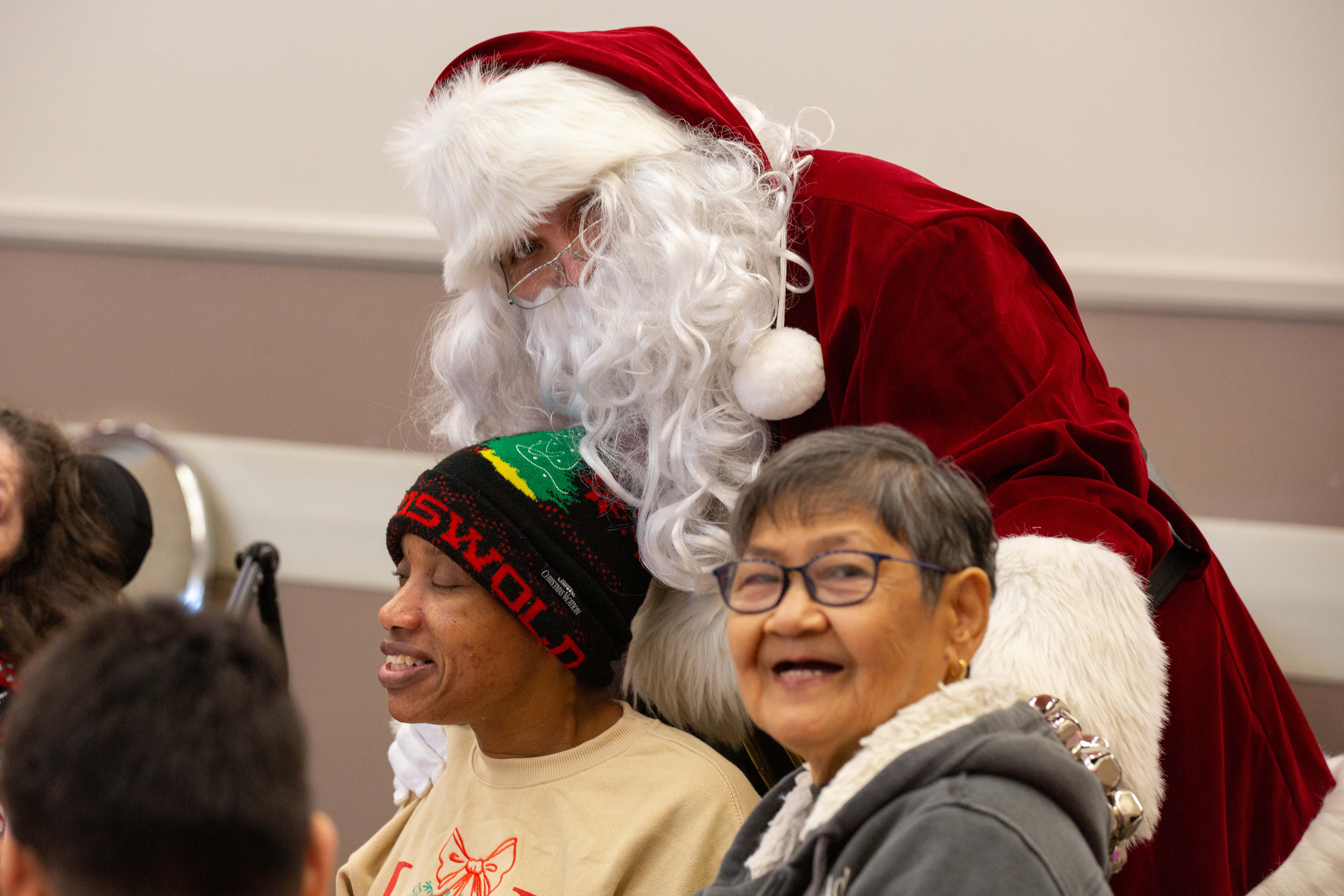 Santa Claus takes a photo with two attendees during the...