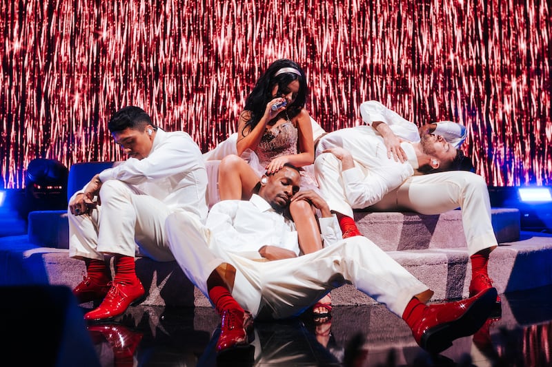 Jesse Murph in pink dress surrounded by dancers in all-white with red shoes.