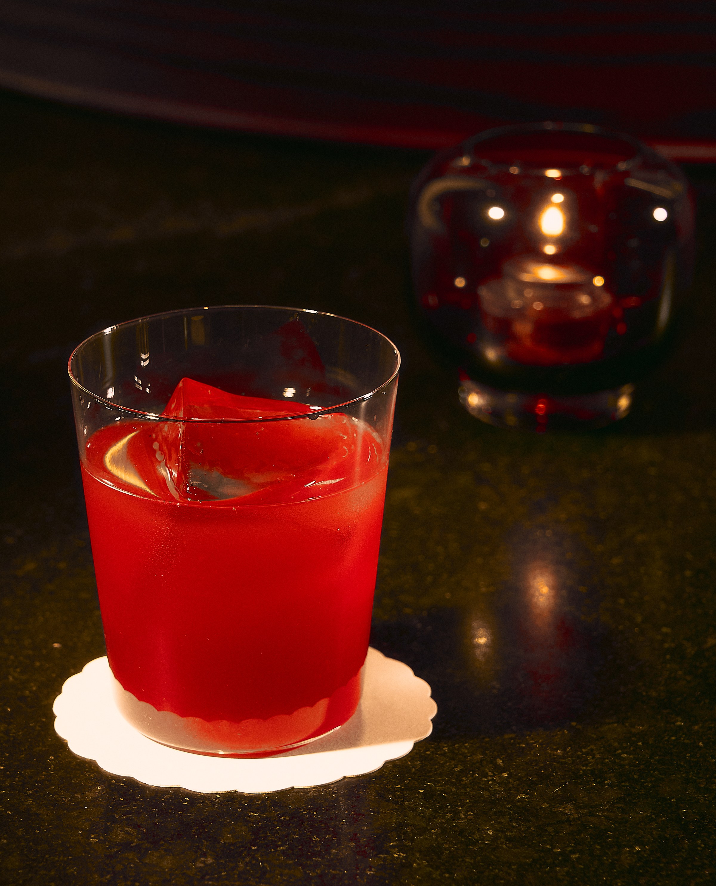 Red-hued cocktail in a glass on a dark bar at Vandell