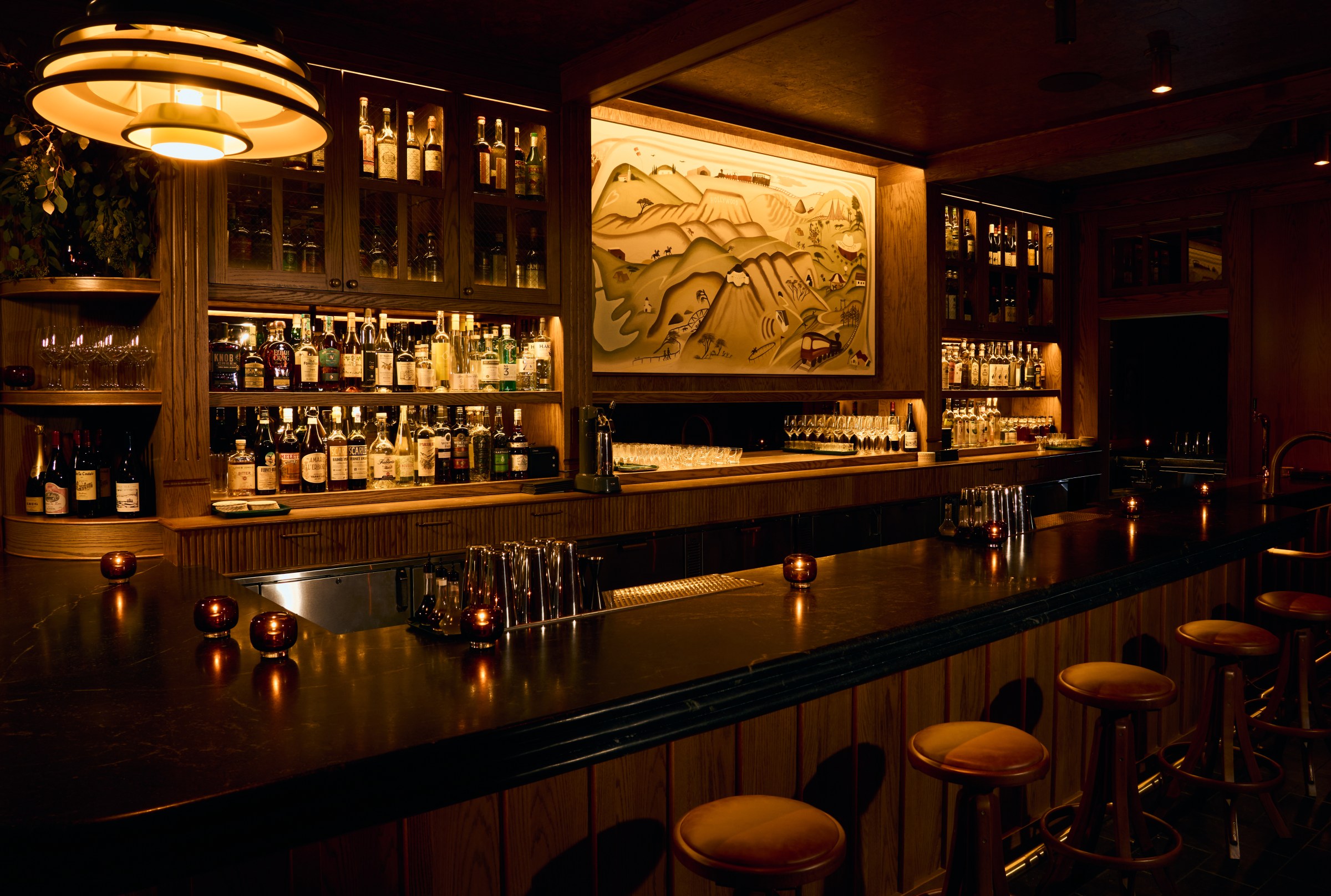 Main bar at Vandell with stools, and a painting over the bar