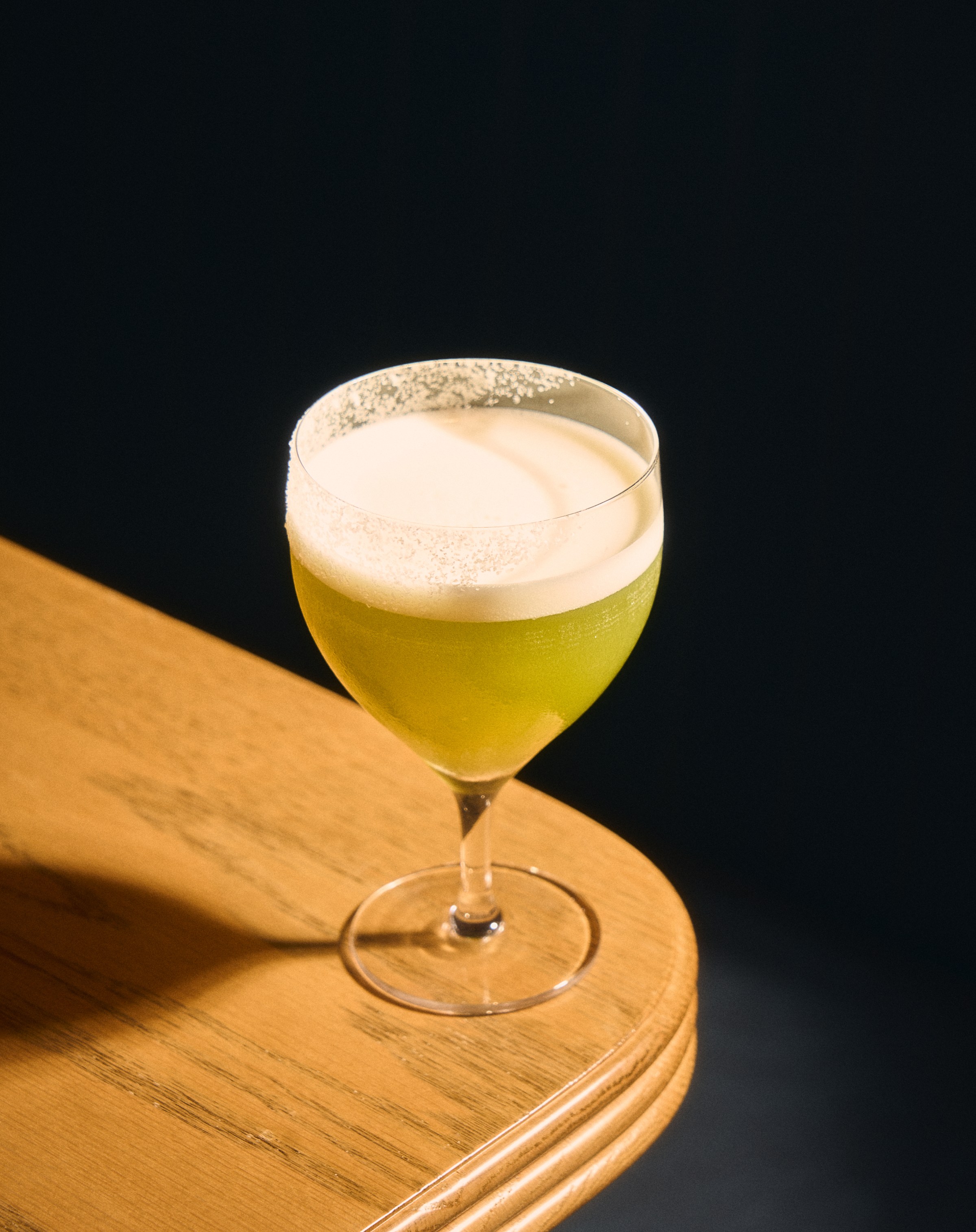 Green-hued drink with foam on top at Vandell