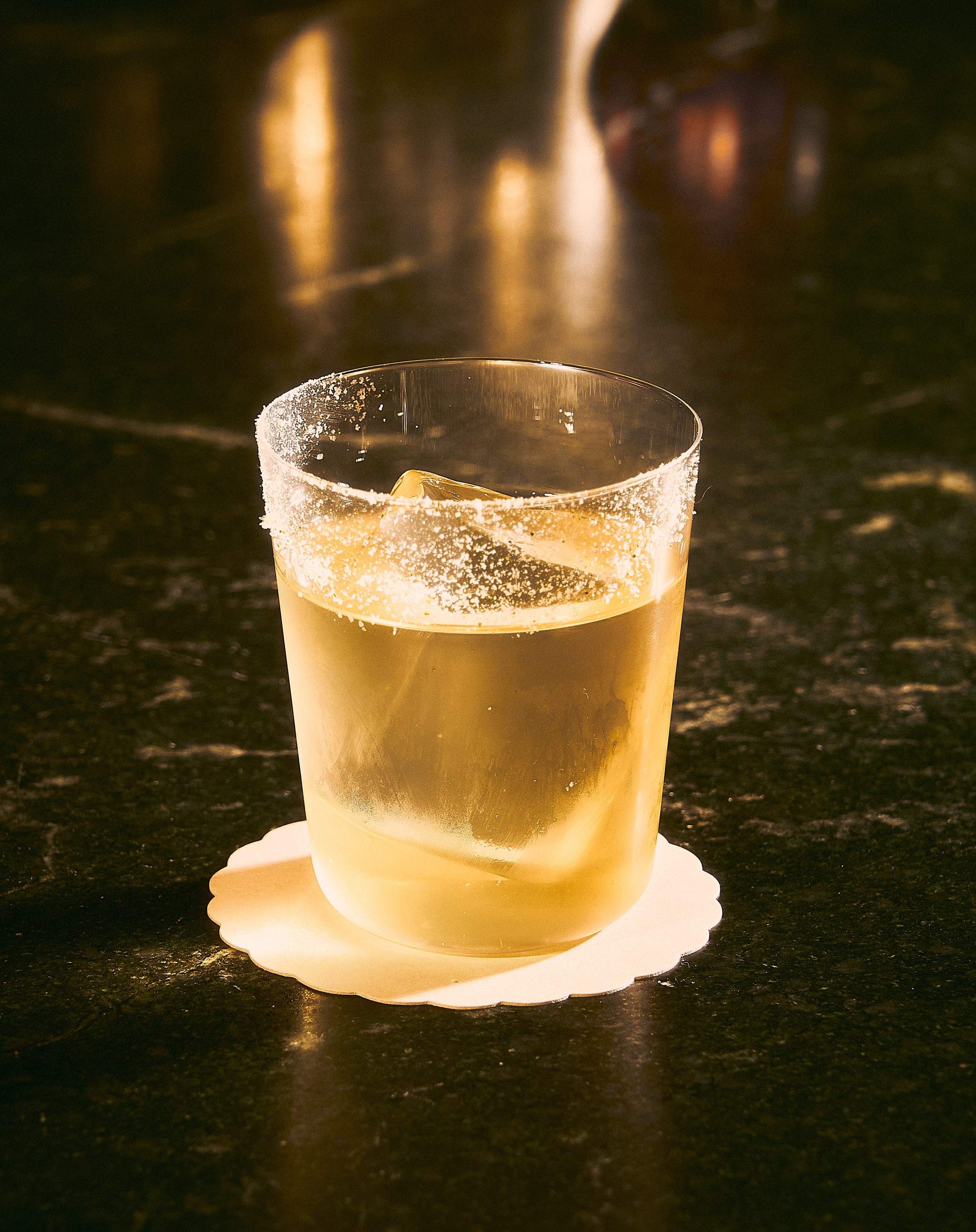 Yellow hued cocktail on a rock in a class at Vandell