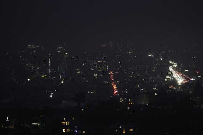 Fog and power outages darken the skyline as traffic moves in San Francisco, Saturday, Dec. 20, 2025. (AP Photo/Jeff Chiu)