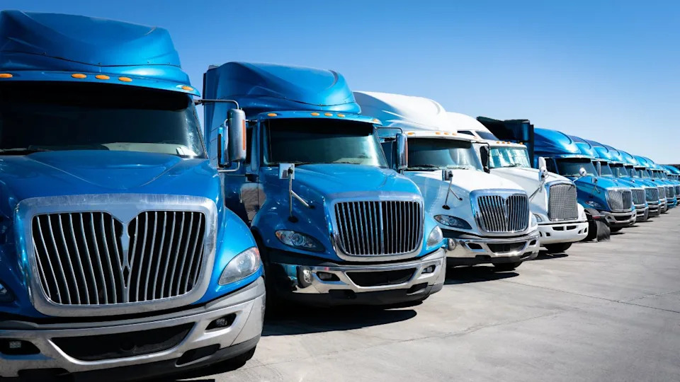 Line of blue 18-wheeler semi-trucks commercial fleet vehicles