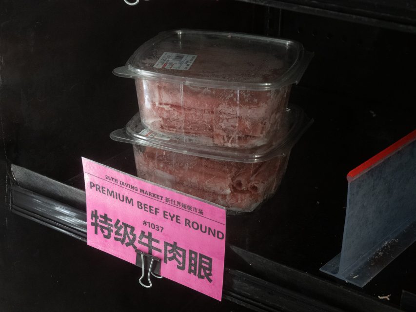 Two plastic containers of sliced beef eye round sit on a shelf above a pink sign labeled "Premium Beef Eye Round" in English and Chinese.