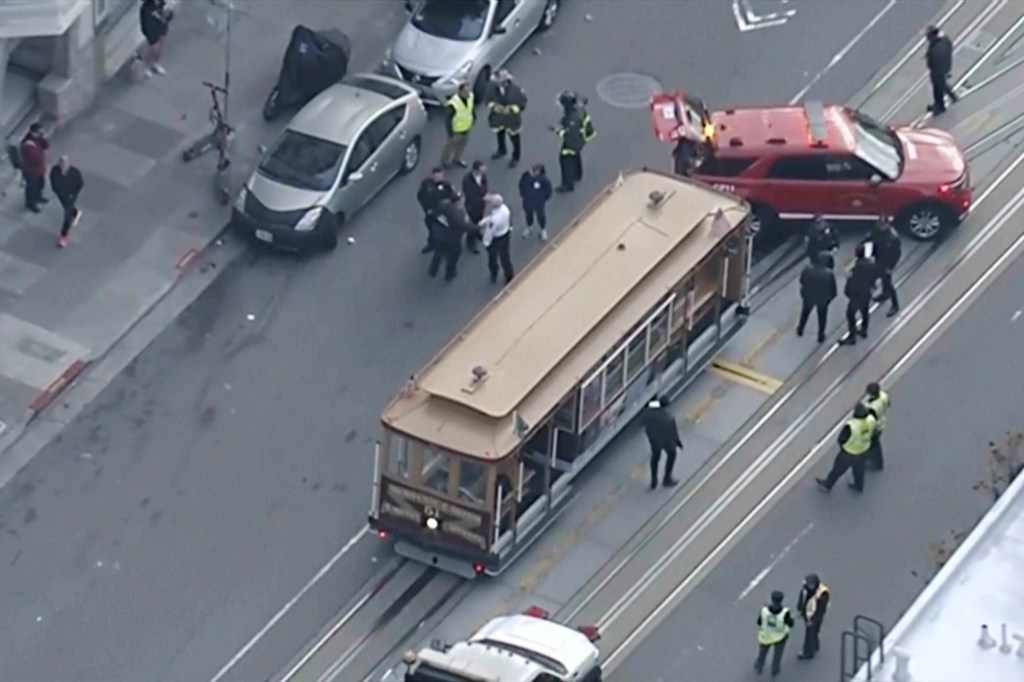 Overhead view of law enforcement and emergency vehicles responding to a cable car's abrupt stop on California Street in San Francisco.