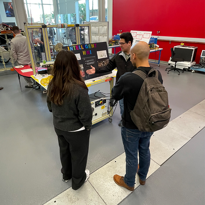student discussing his project to event attendees