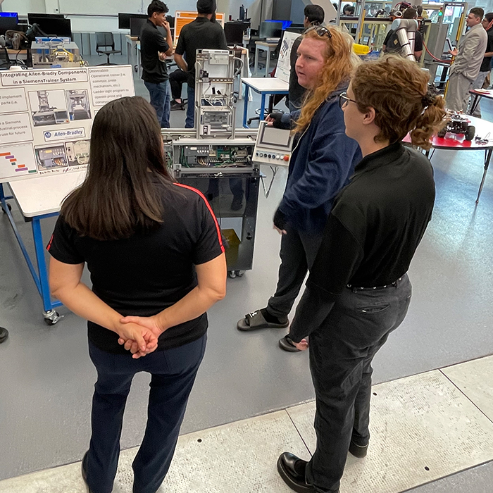 male student discussing his project with two onlookers