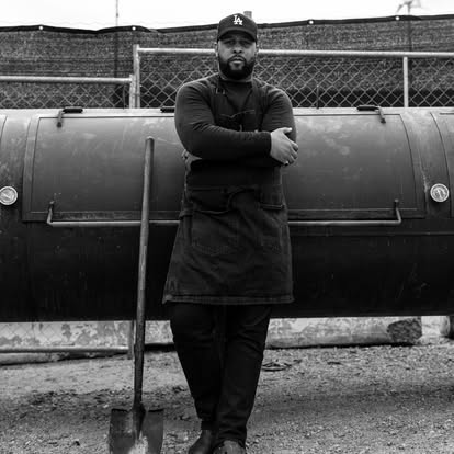 a man standing in front of a barbecue smoker