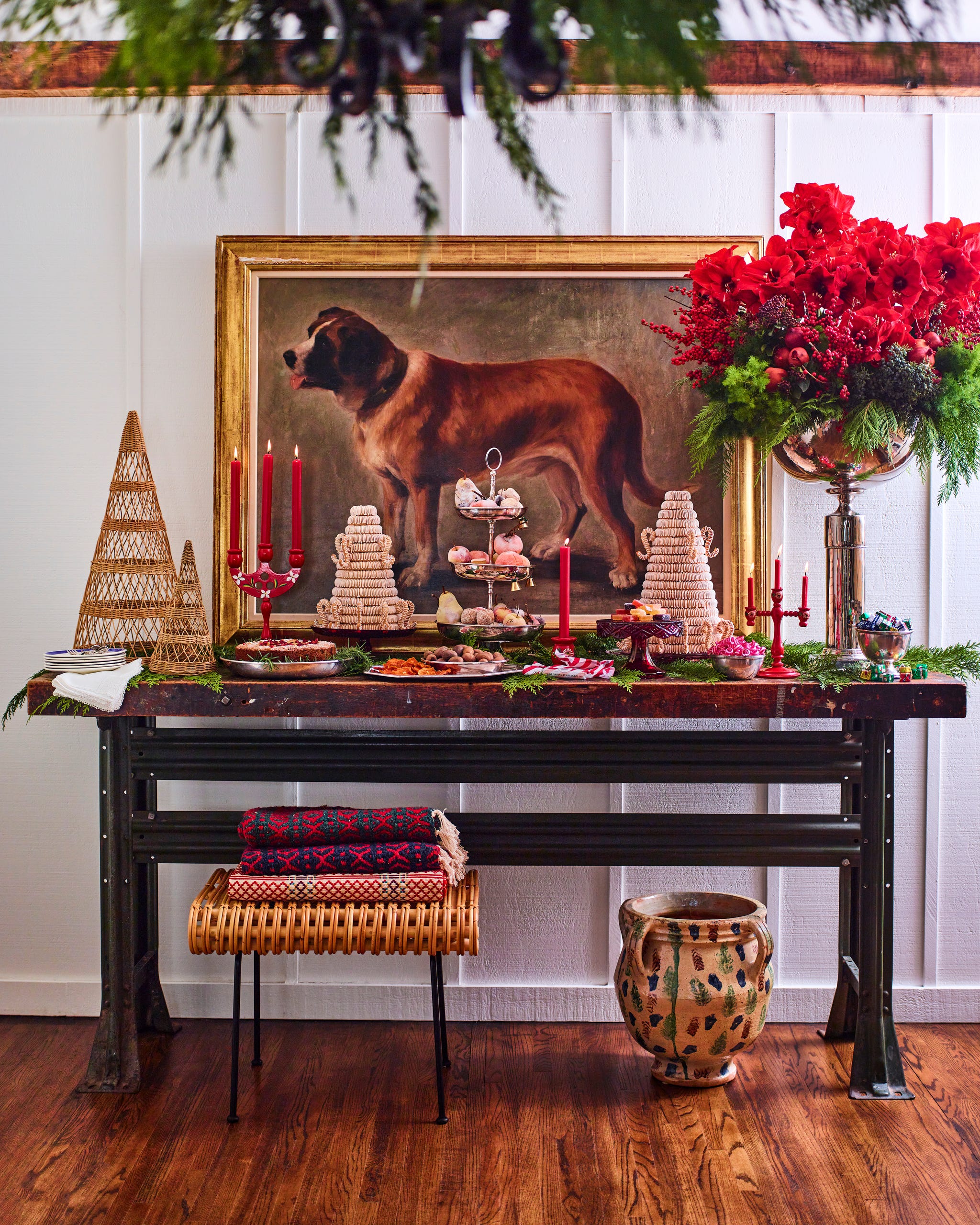buffet topped with various desserts and holiday decorations with a painting of a dog hanging above it