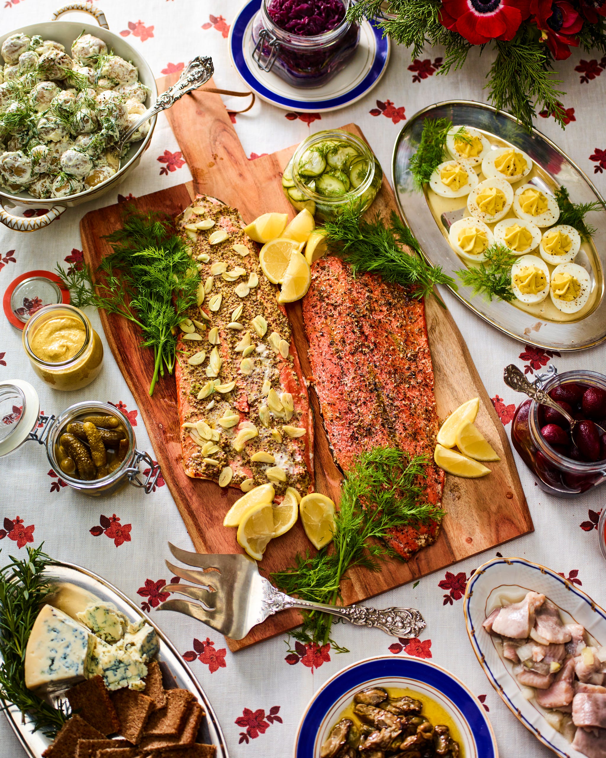 platter serving salmon surrounded by plates with deviled eggs, potatoes, and other dishes