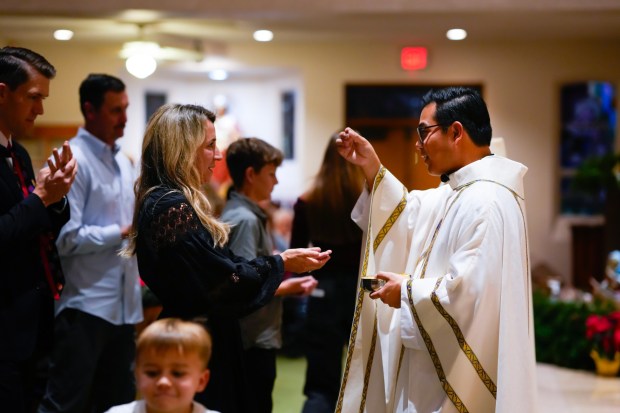 Father Brian Frulla offers communion to parishioners during Christmas Eve Mass at St. Therese Catholic Church in the Del Cerro Community of San Diego.  Frulla is one of three men who were ordained in June and celebrated mass as new priests.  (Nelvin C. Cepeda / The San Diego Union-Tribune)