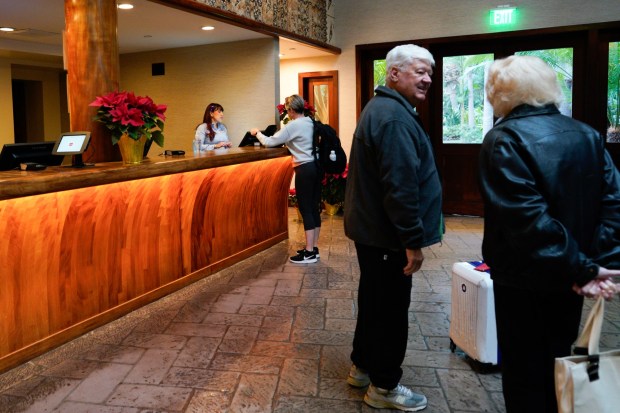 Front desk clerk at the Catamaran Hotel, Joanna Castro, assists a hotel guest with checking in on Friday.  (Nelvin C. Cepeda / The San Diego Union-Tribune)