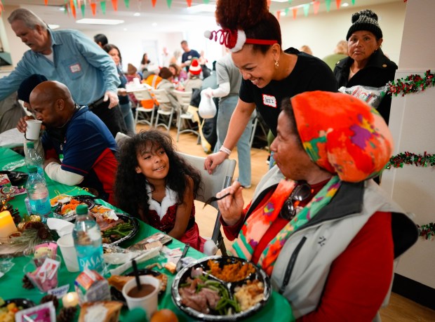 Jazmin Ernest from the San Diego Rescue Mission chatted with Faith Evans, 62, and her granddaughter, Malajah Moore, 8, who were enjoying their Christmas meal.  The two live nearby in an apartment not far from downtown.  An estimated 900 folks enjoyed a warm Christmas meal at the San Diego Rescue Mission on Saturday, Dec. 20, 2025, in San Diego, CA.   (Nelvin C. Cepeda / The San Diego Union-Tribune)