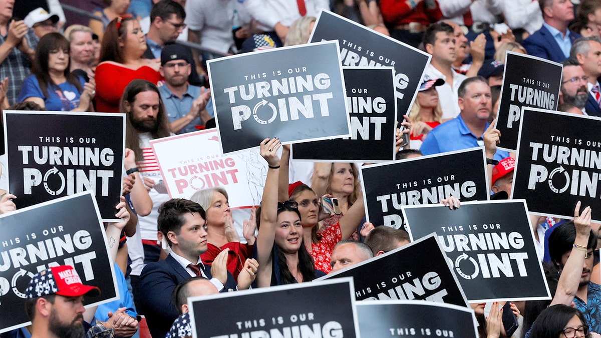 People holding "This is our Turning Point" signs during a memorial for Charlie Kirk