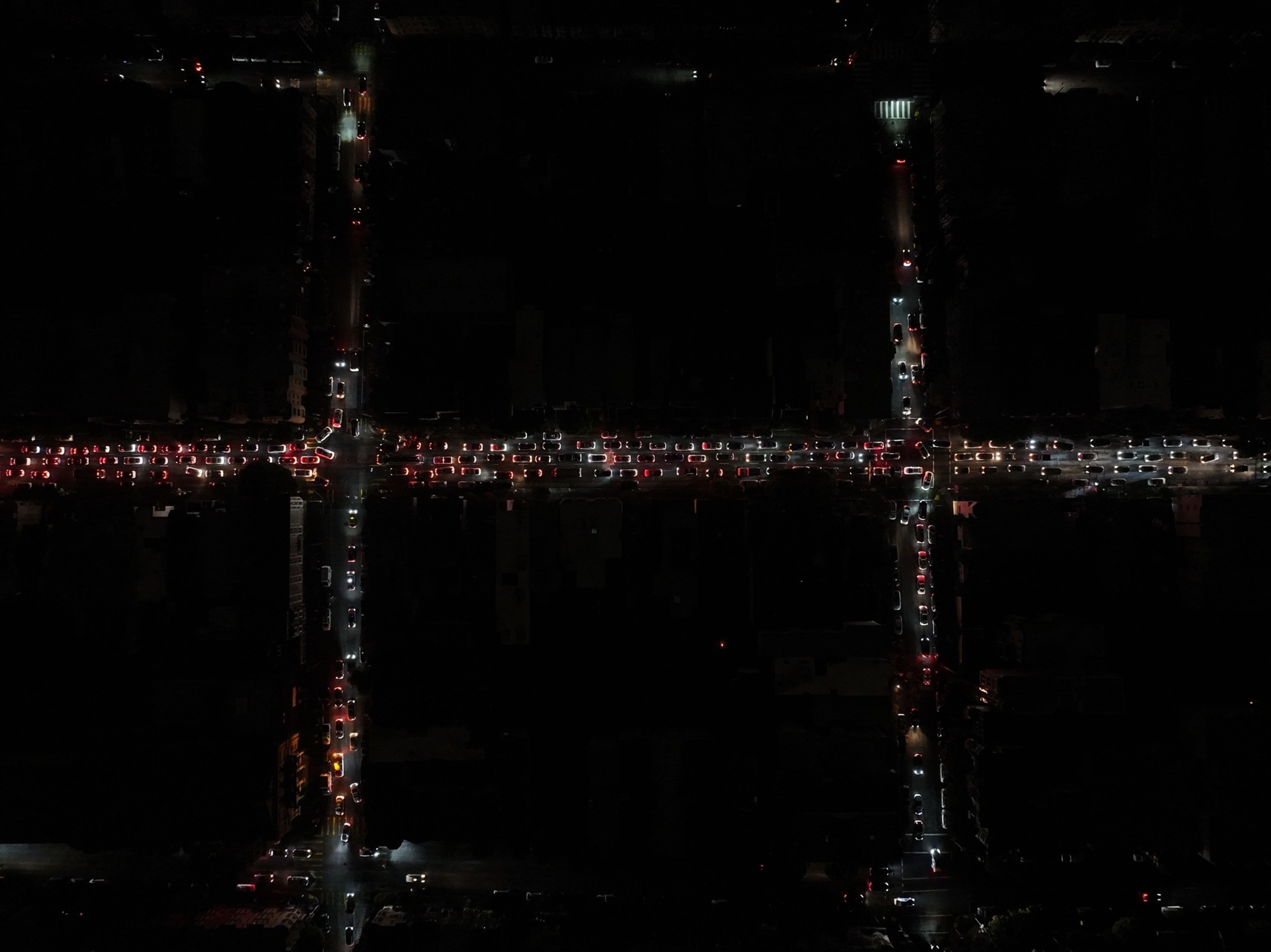 Cars with headlights and taillights create dense traffic along intersecting city streets at night.