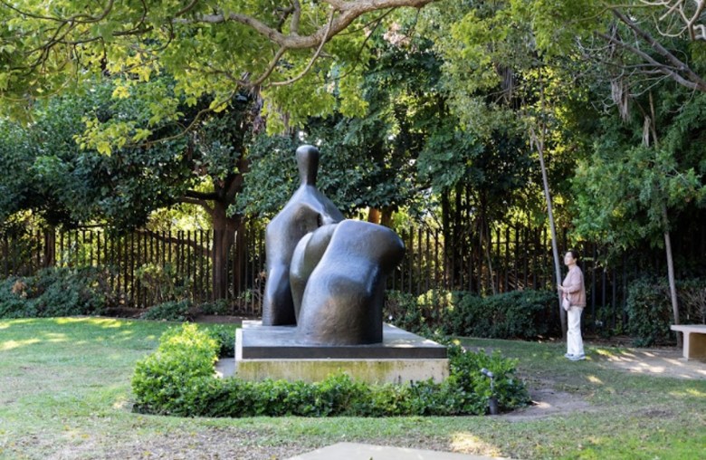 A contemporary sculpture beneath a tree in an outdoor setting.