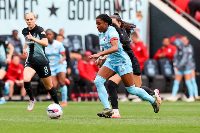 A woman controls the ball as players pursue on the soccer pitch. The central player is Ludmila.