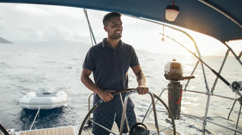 Smiling young man as helmsman on sailboat
