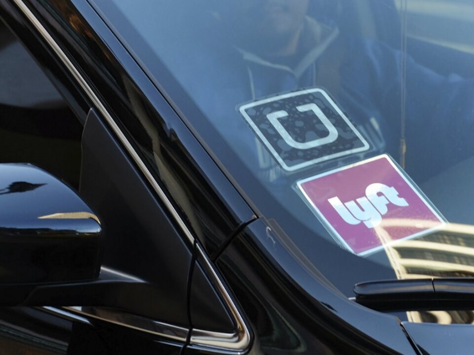 A close up of a car's windshield with an Uber and Lyft sticker.